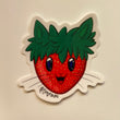 Art sticker of a red strawberry with a cute happy kitty face with whiskers on it, the green leaf portion on the top of the strawberry looks like two cat ears.